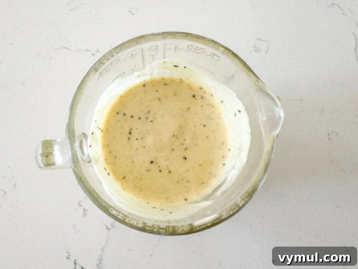 Pantry Powerhouse Protein Chicken Salad 5 Dressing ingredients for chicken salad, including yogurt, mayonnaise, mustard, and spices, mixed in a measuring cup.