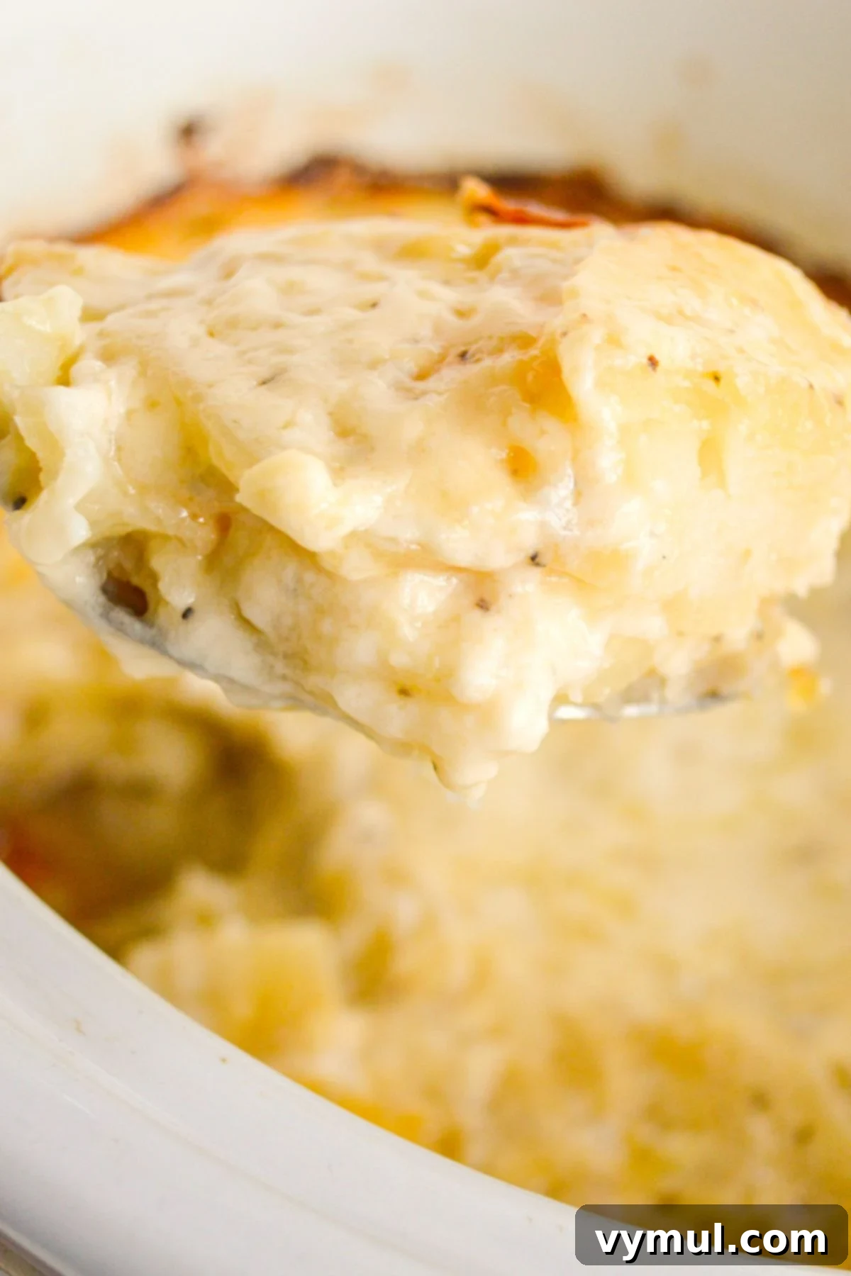 Irresistible Slow Cooker Cheesy Garlic Scalloped Potatoes 2 scalloped potatoes on a serving spoon