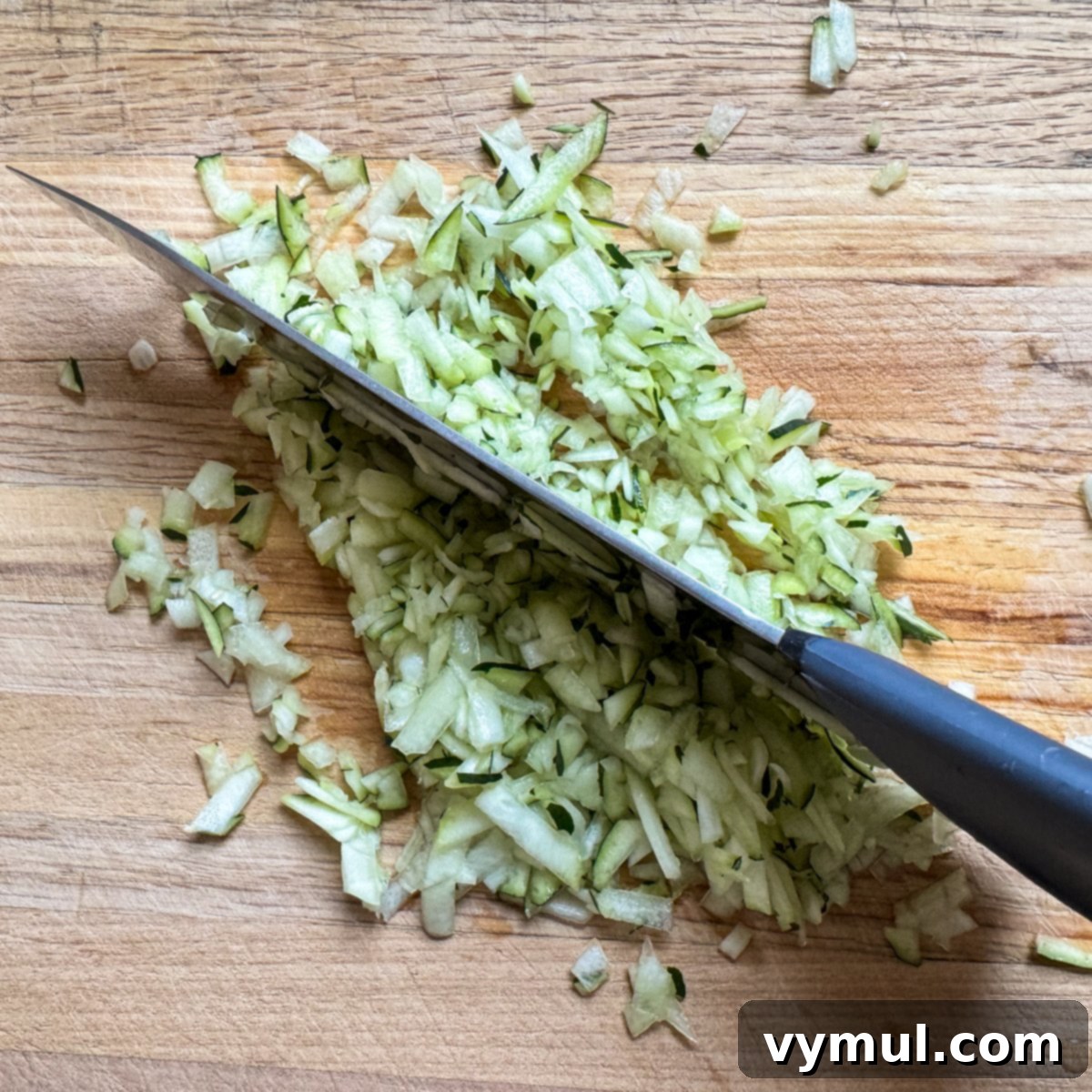 Finely chopping grated zucchini on a cutting board