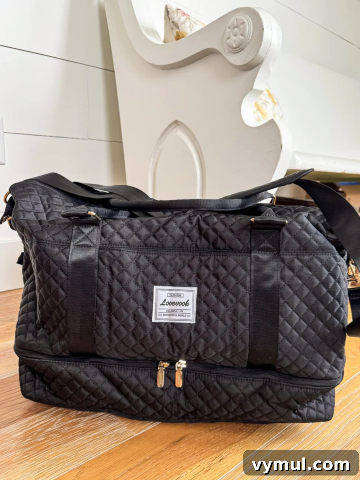 Stylish black quilted weekender bag resting on a warm wooden floor, ready for travel