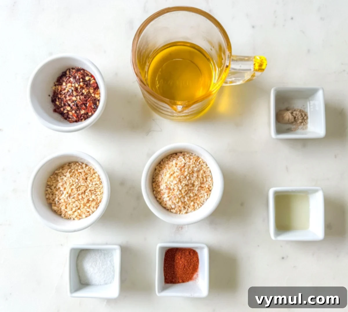 Close-up of chili crisp ingredients laid out: olive oil, dried onions, dried garlic, red pepper flakes, salt, and paprika