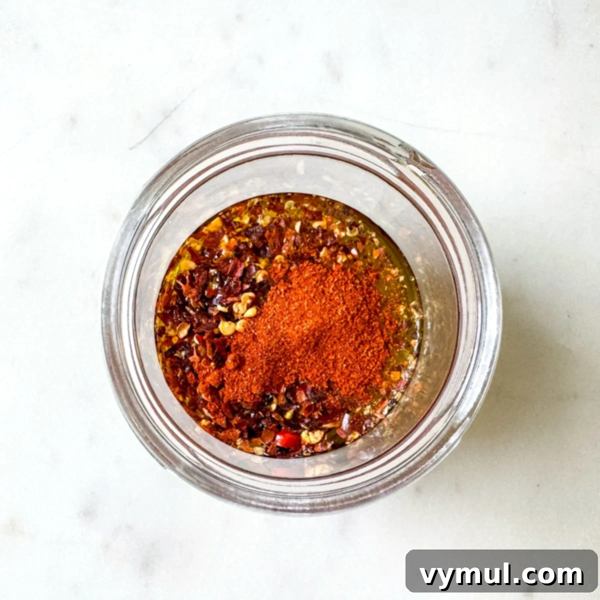 Olive oil, red pepper flakes, and paprika mixed in a small glass jar