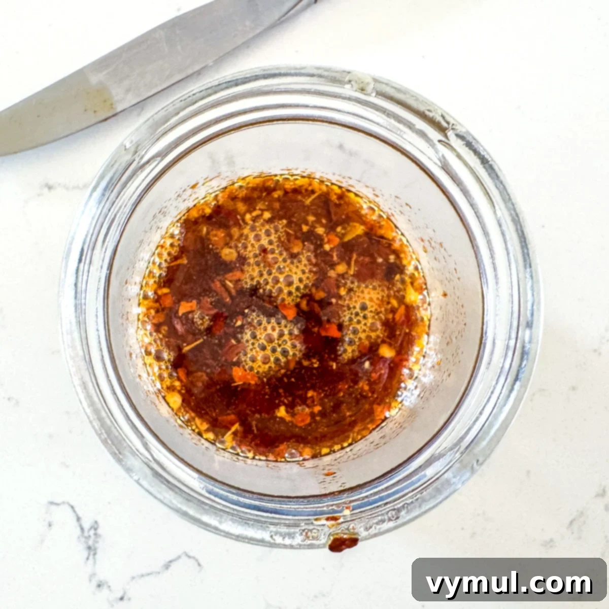 Chili crisp mixture gently bubbling in a glass jar, indicating optimal heating